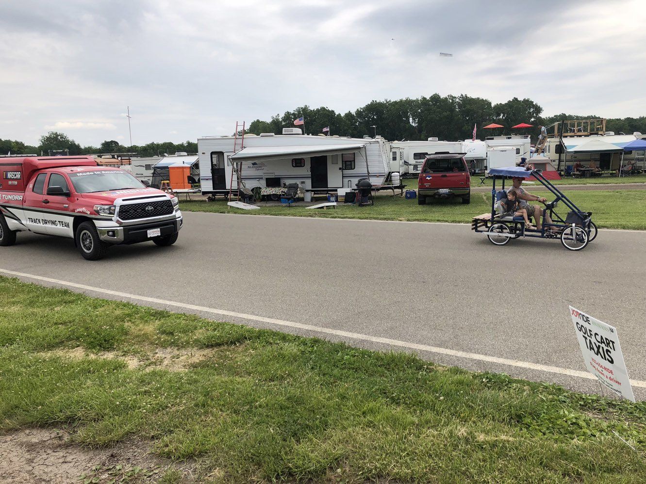 A truck is driving down a road next to a trailer.