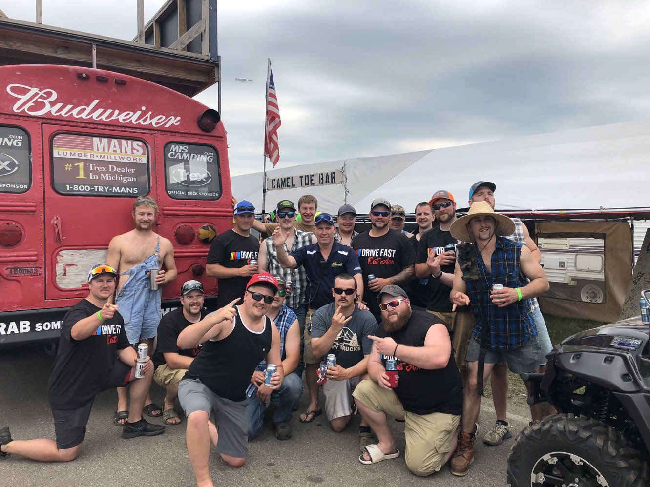A group of men are posing for a picture in front of a budweiser bus.