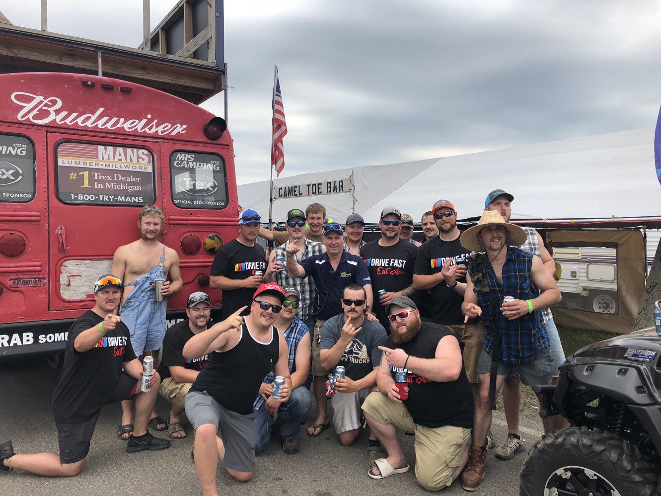 A group of men are posing for a picture in front of a budweiser bus.