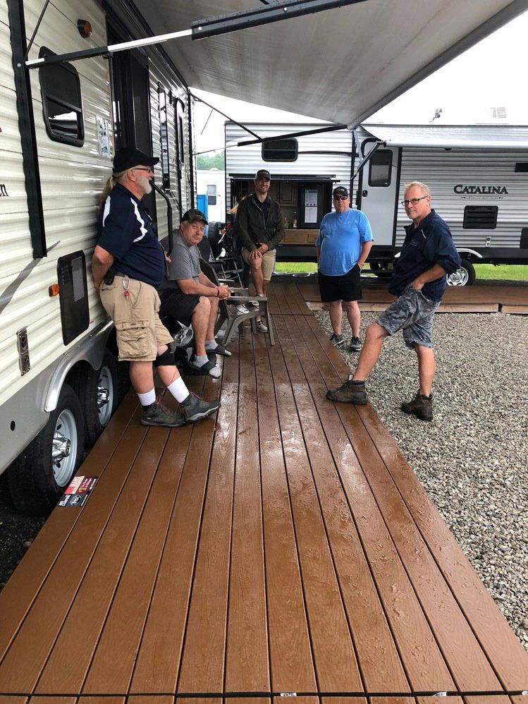 A group of men are standing on a deck next to a trailer.