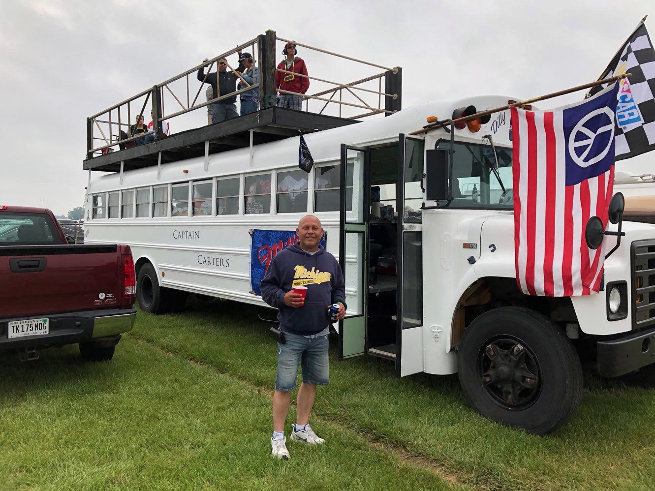 A man is standing in front of a double decker bus.