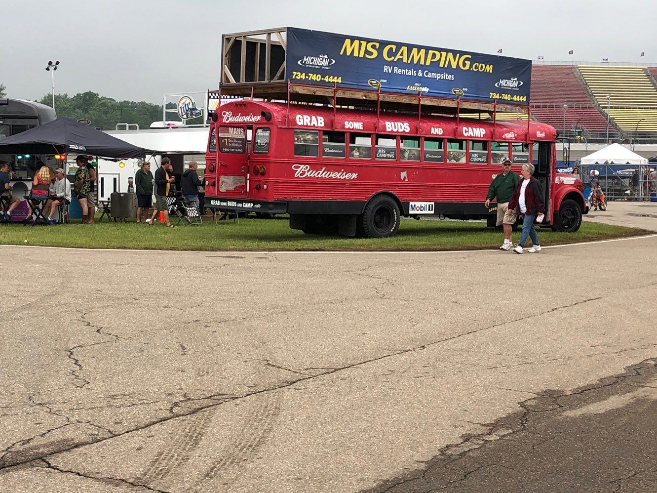 A red bus with a sign on top that says mis camping