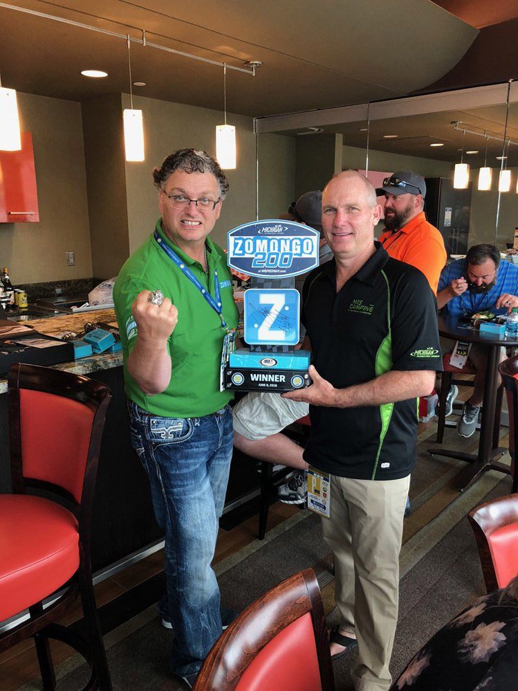 Two men standing next to each other holding a sign that says z on it