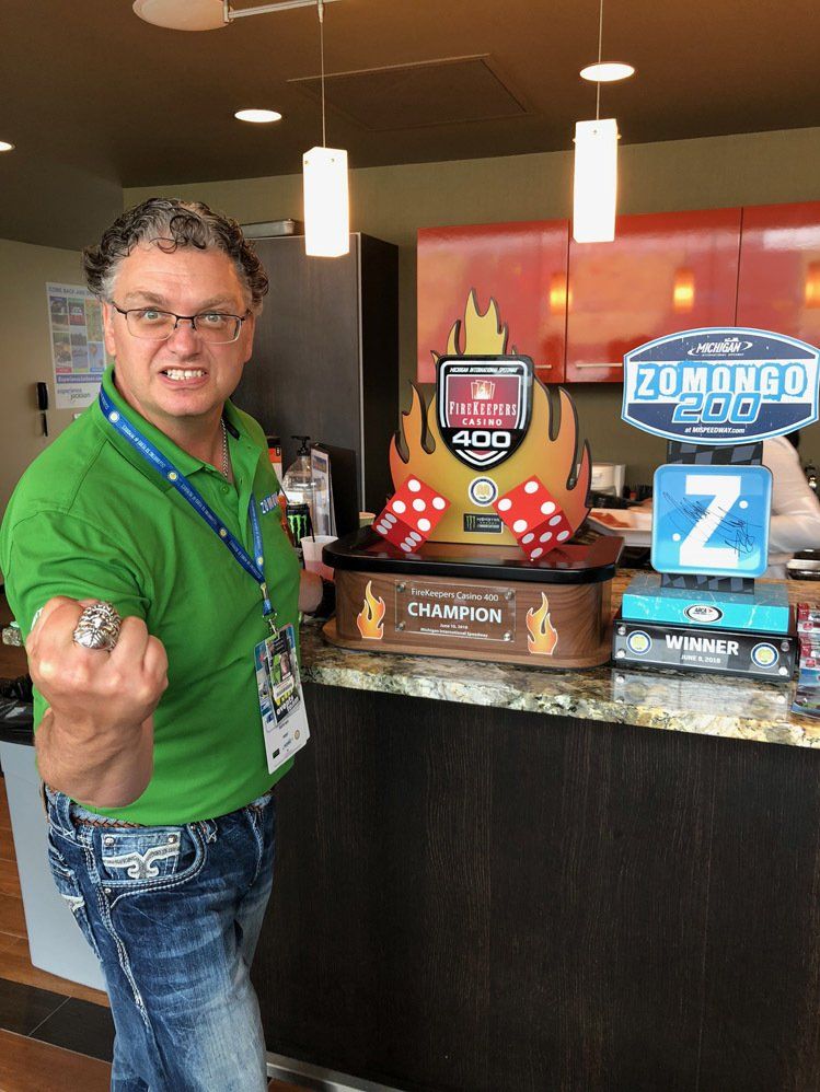 A man in a green shirt is standing in front of a counter with dominoes on it