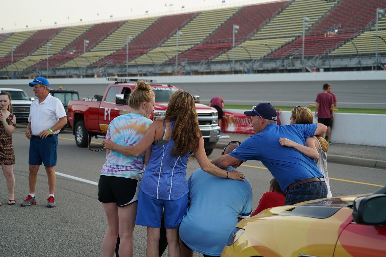 A group of people are hugging each other in front of a race track.