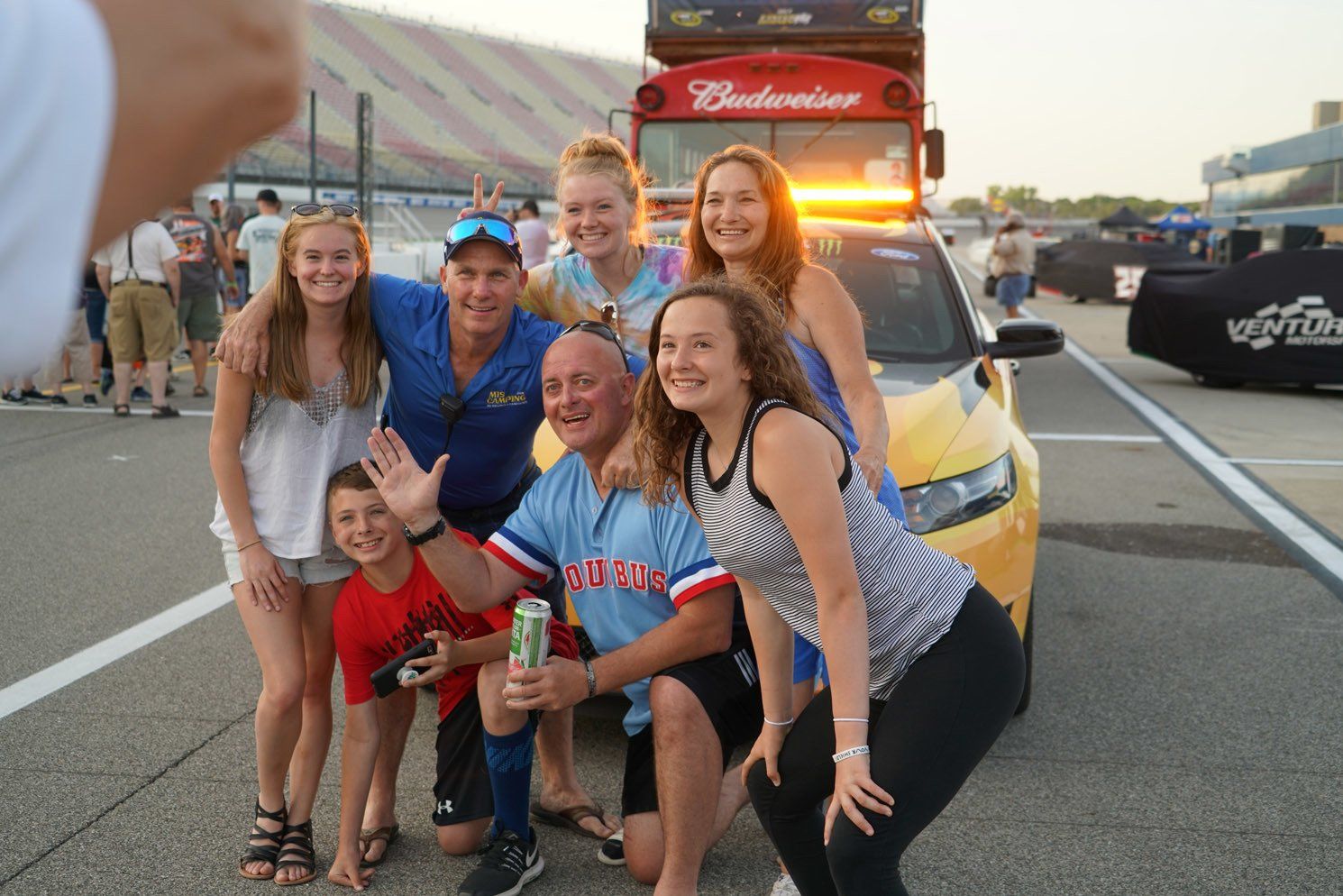 A group of people posing for a picture in front of a budweiser bus