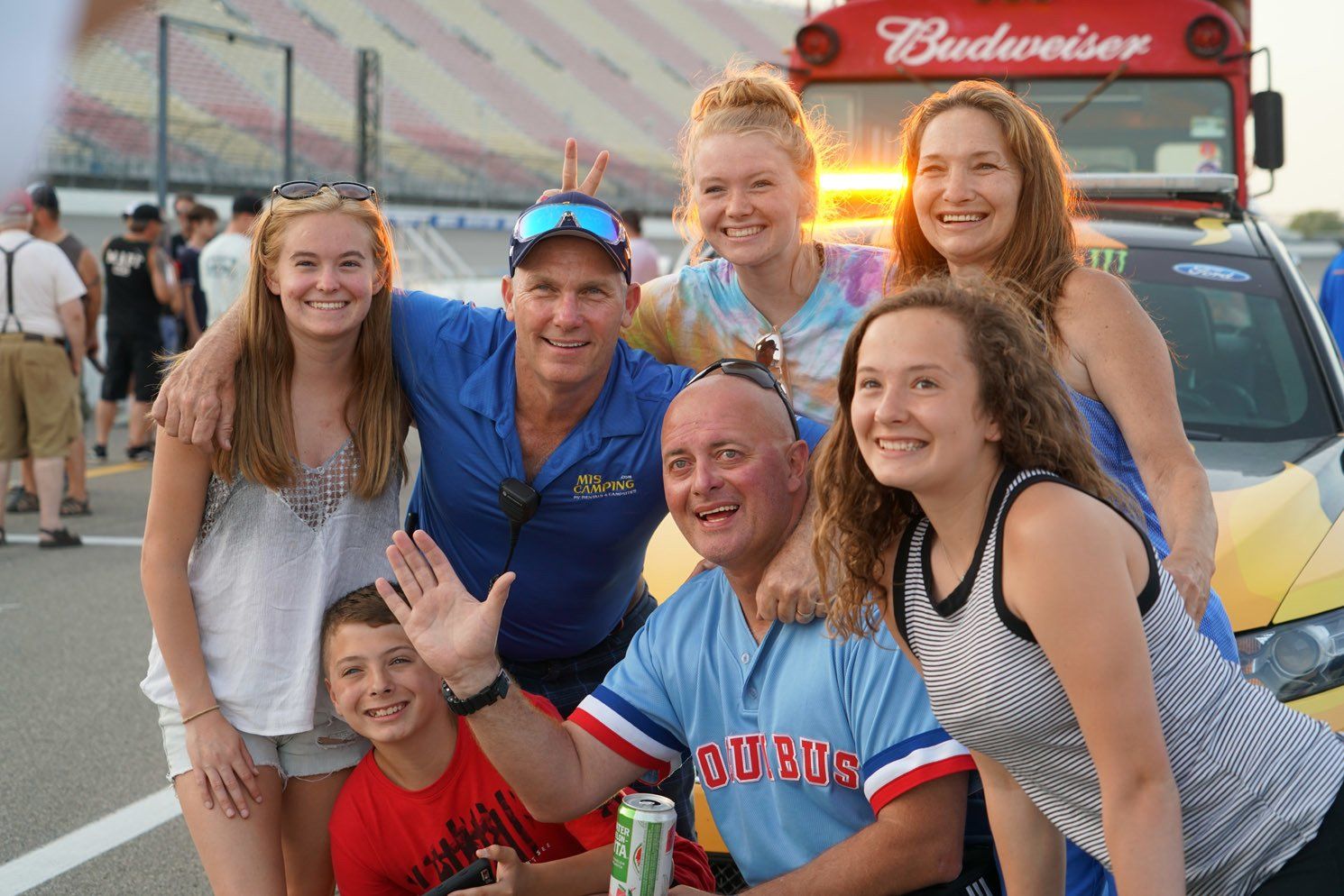 A group of people posing for a picture in front of a budweiser bus