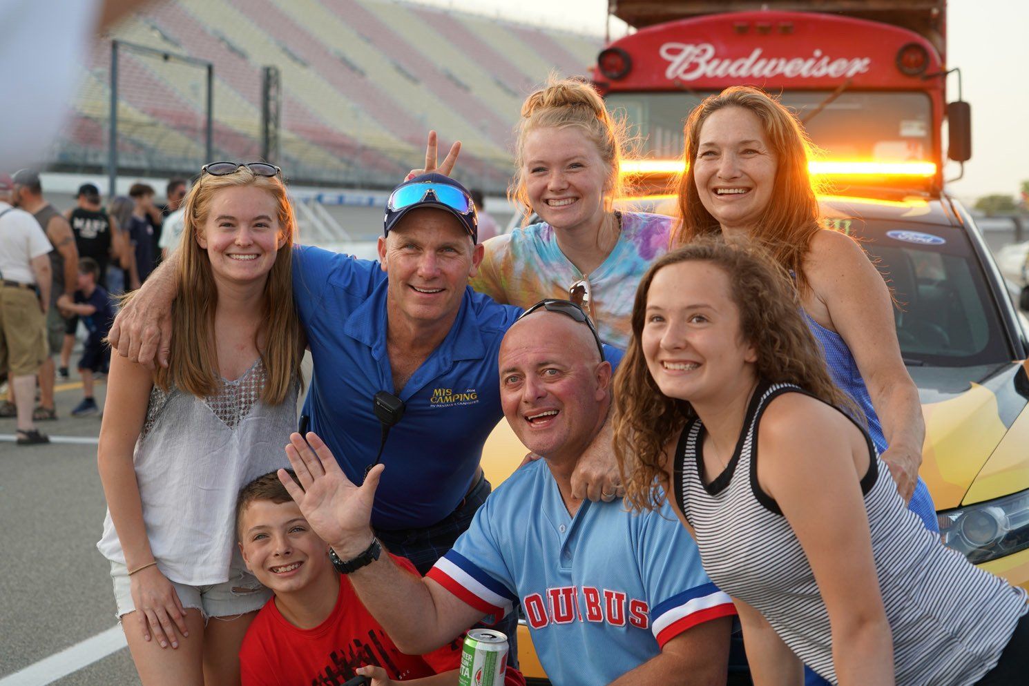 A group of people posing for a picture in front of a budweiser bus
