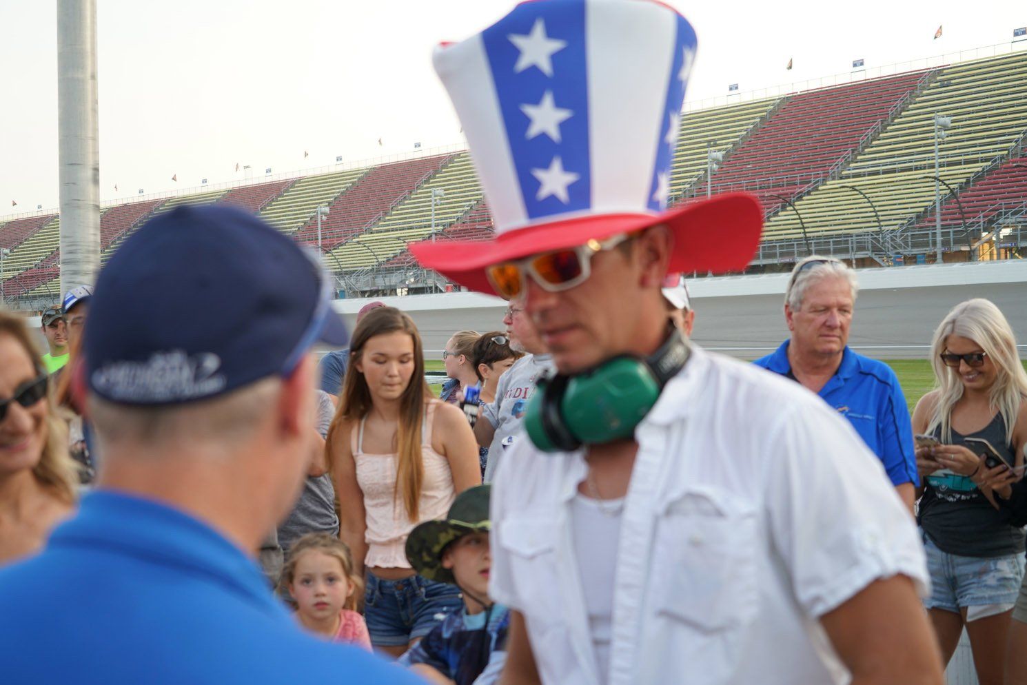 A man wearing an uncle sam hat and headphones is talking to another man.