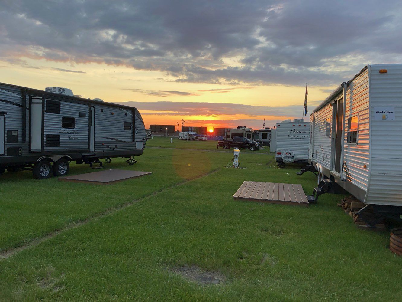 A group of trailers are parked in a field at sunset.