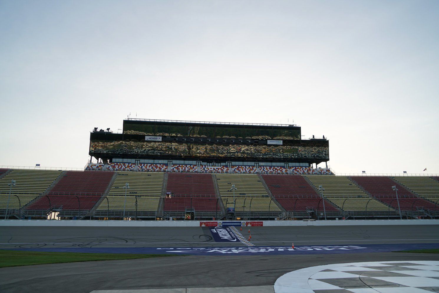 A race car is driving down a race track in front of an empty stadium.