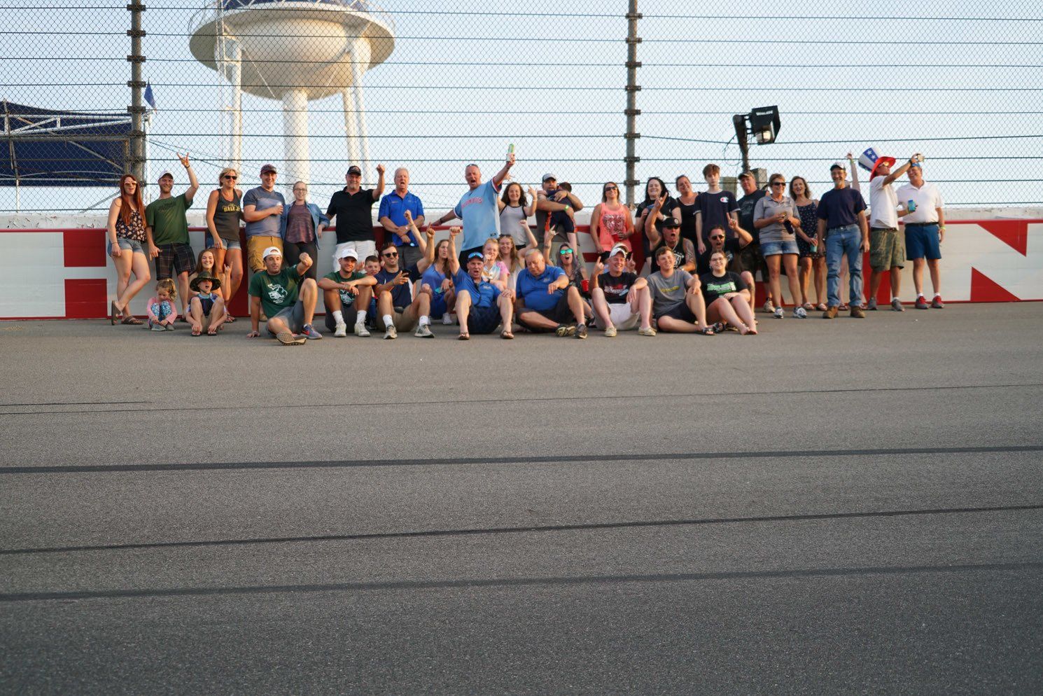 A group of people are posing for a picture on a race track