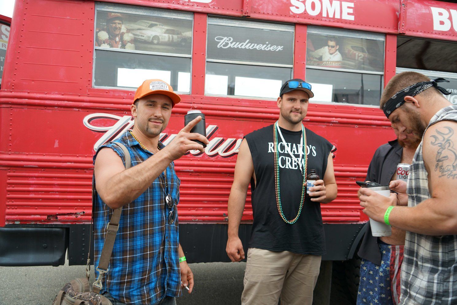 A group of men are standing in front of a budweiser bus