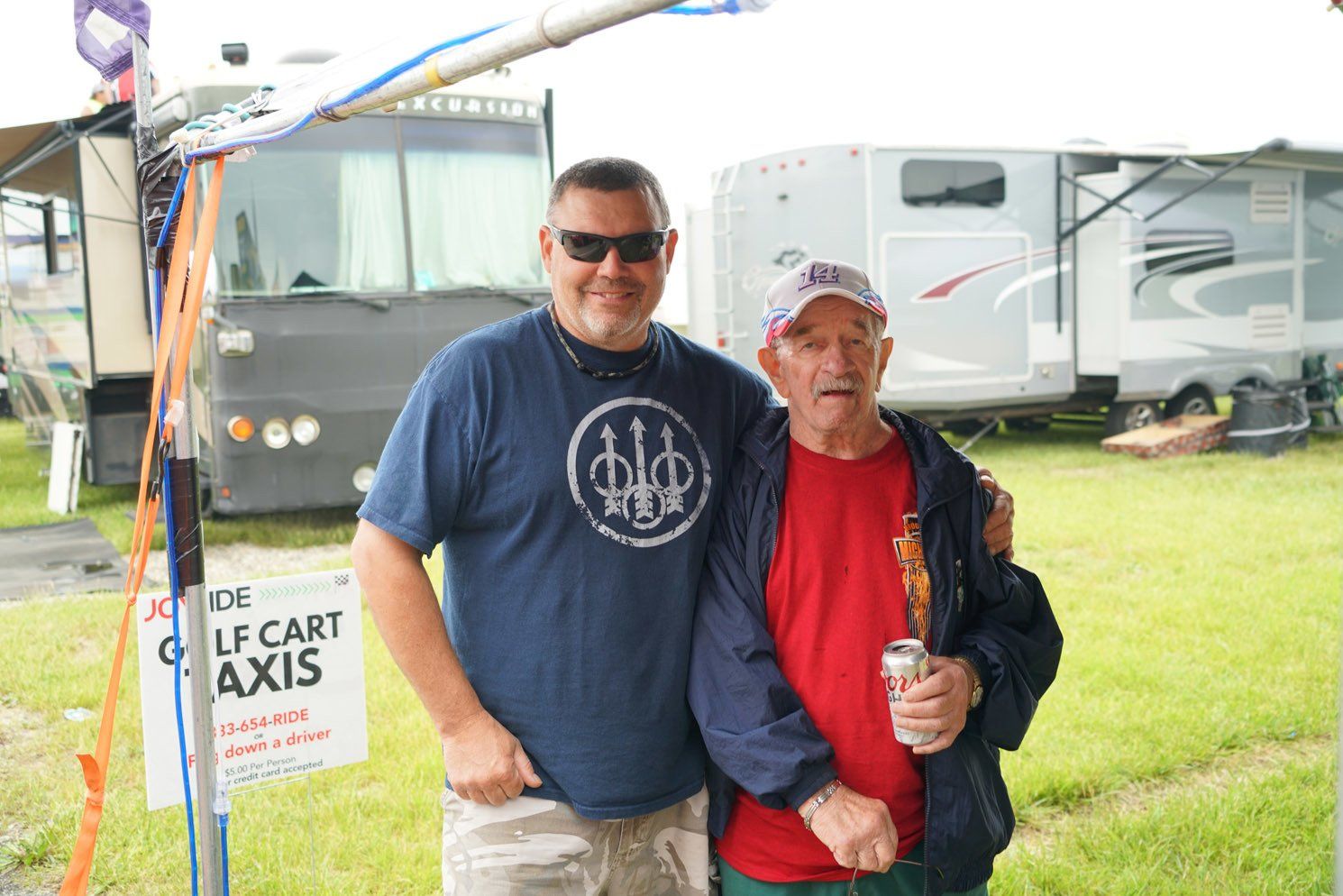 Two men standing in front of a sign that says gulf cart axis