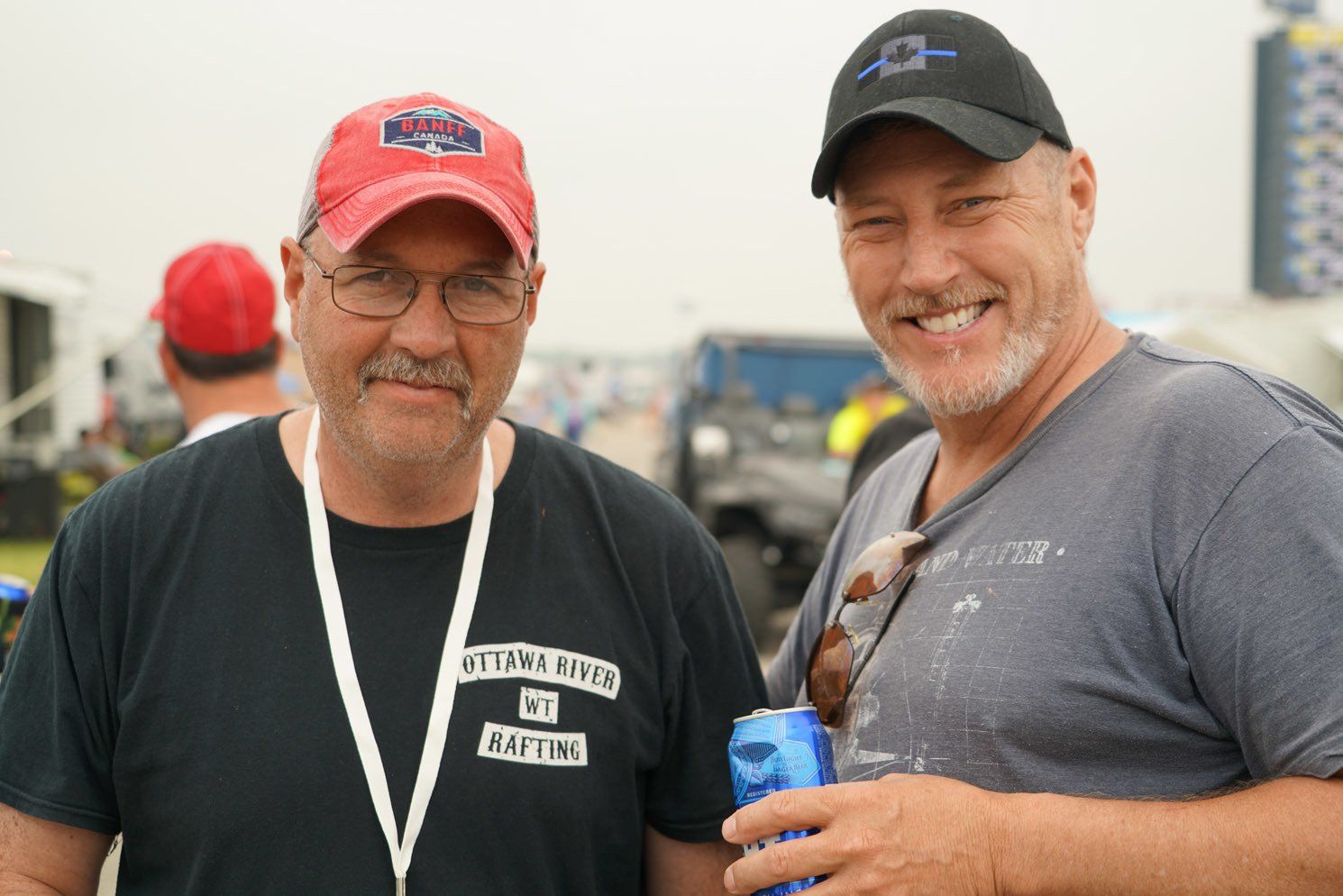 Two men are posing for a picture and one has a lanyard around his neck