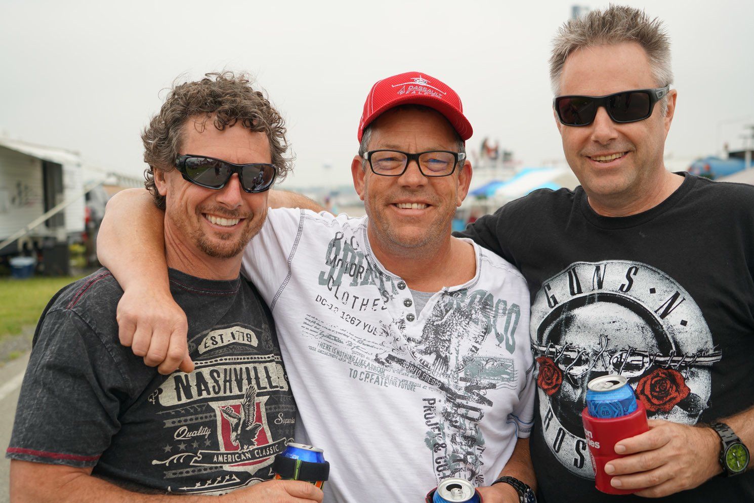 Three men posing for a picture with one wearing a nashville shirt