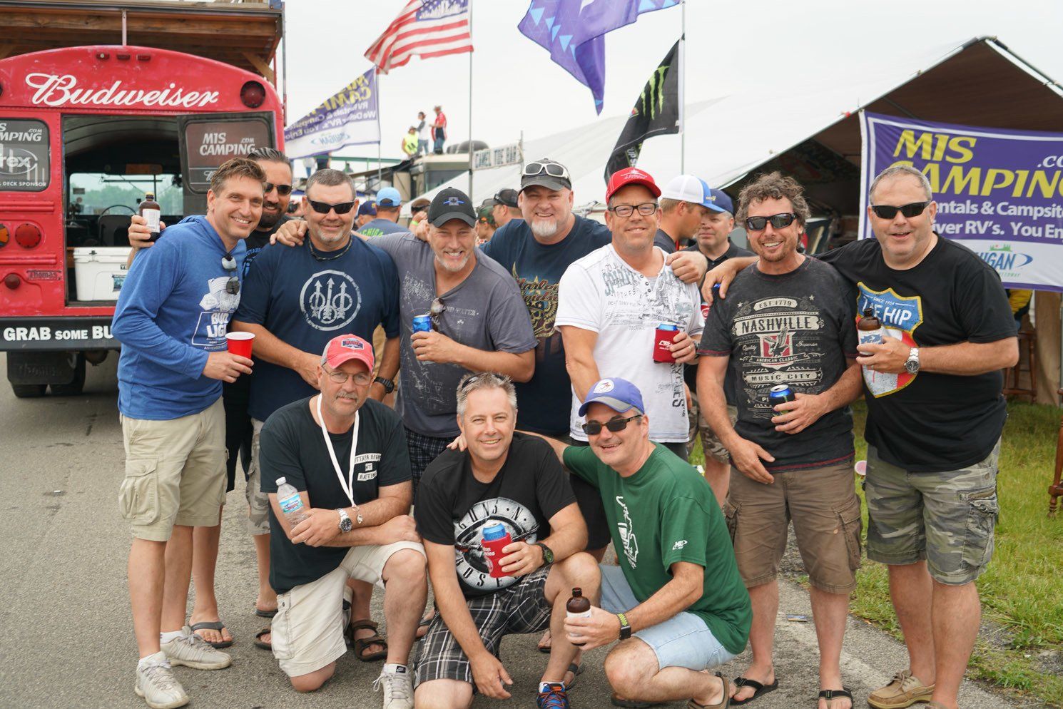 A group of men posing for a picture in front of a budweiser bus
