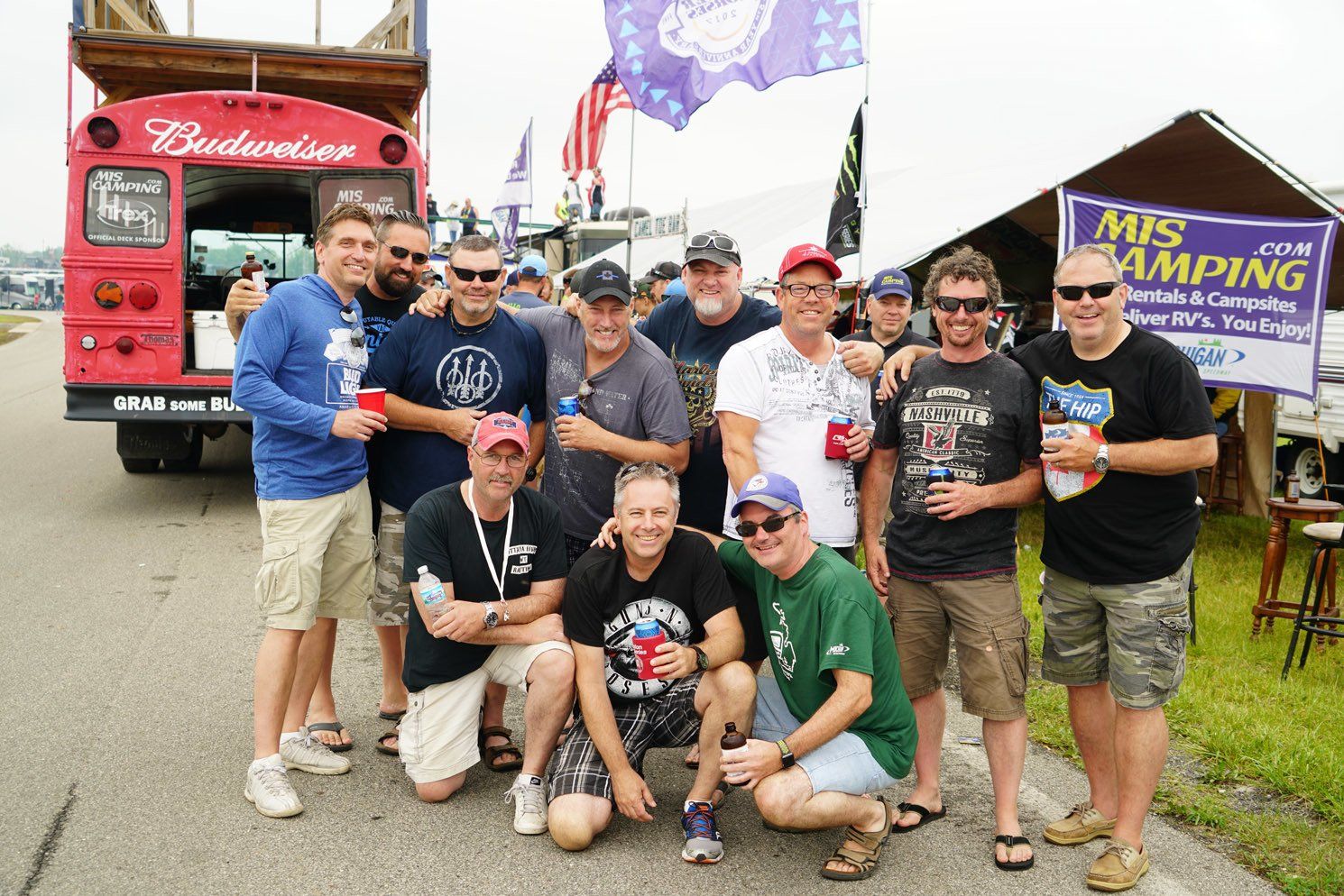 A group of men are posing for a picture in front of a budweiser bus