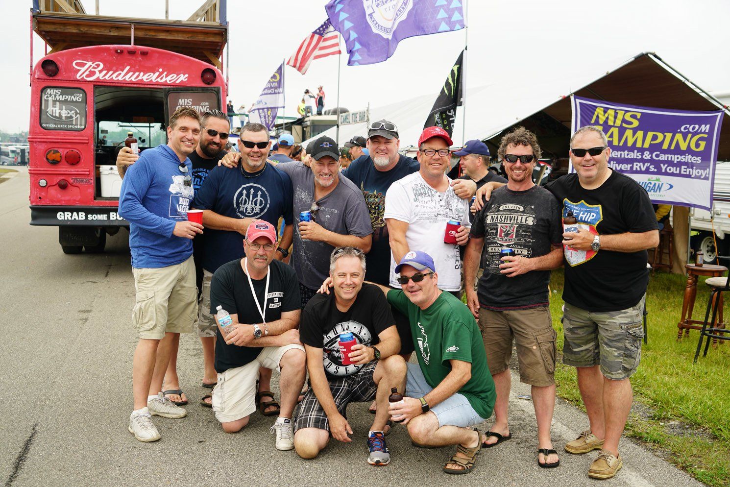 A group of men are posing for a picture in front of a budweiser bus