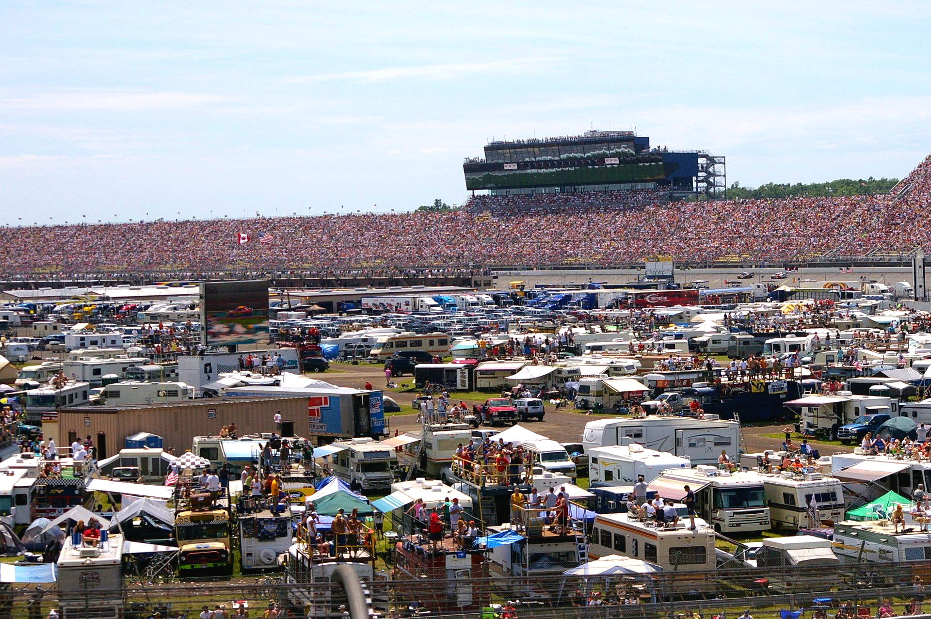 A large group of people are gathered in a field at a race track.