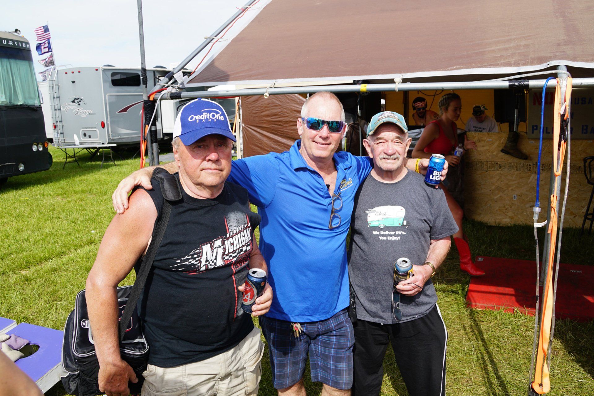 Three men are posing for a picture in front of a tent.