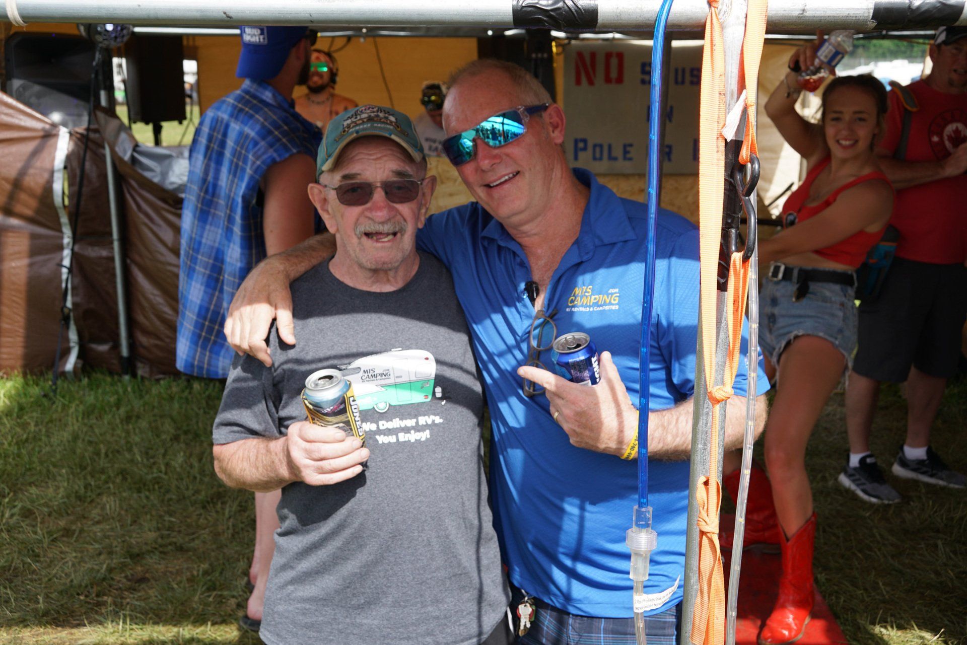 Two men are posing for a picture and one is holding a can of beer