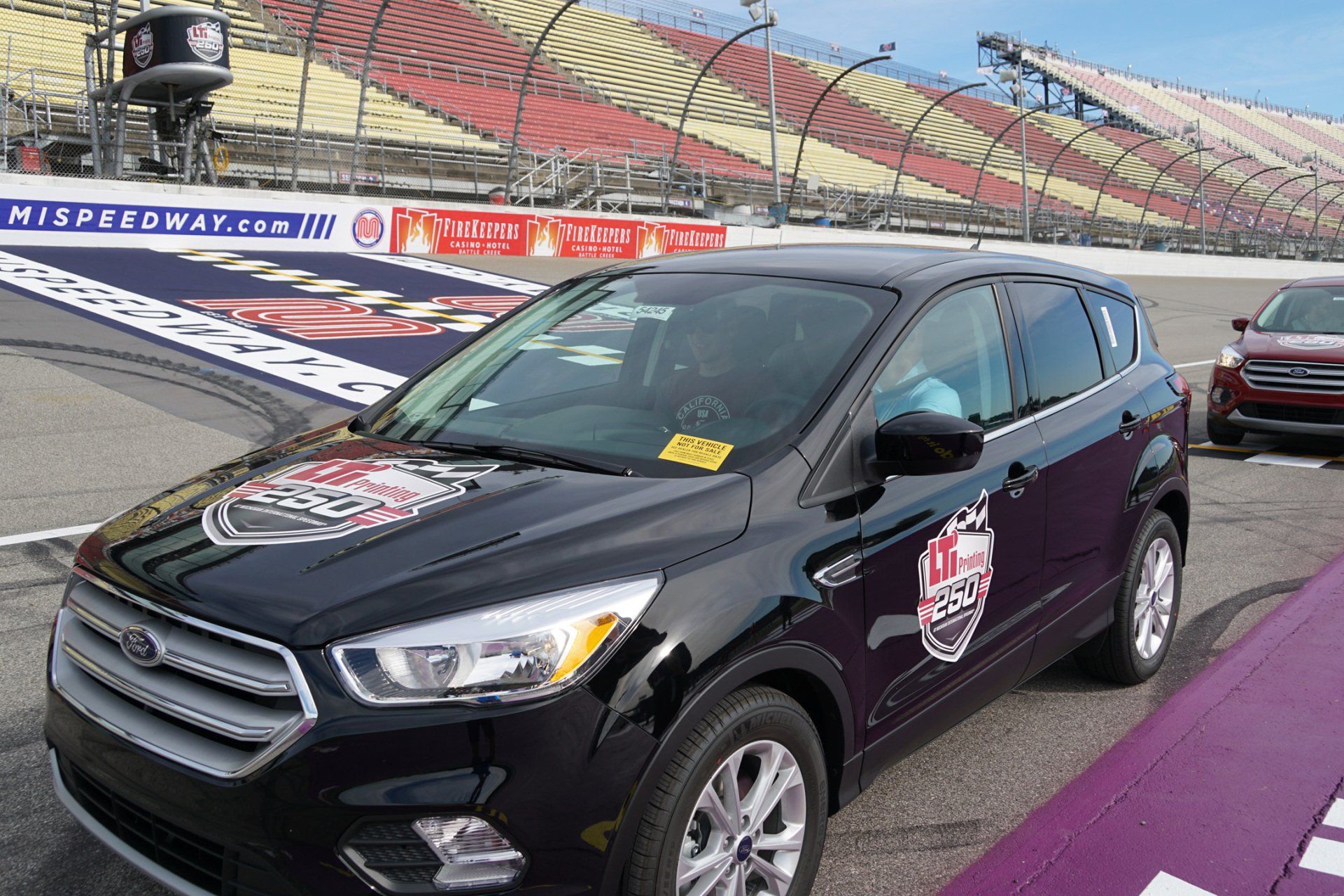 A black ford car is parked on a race track