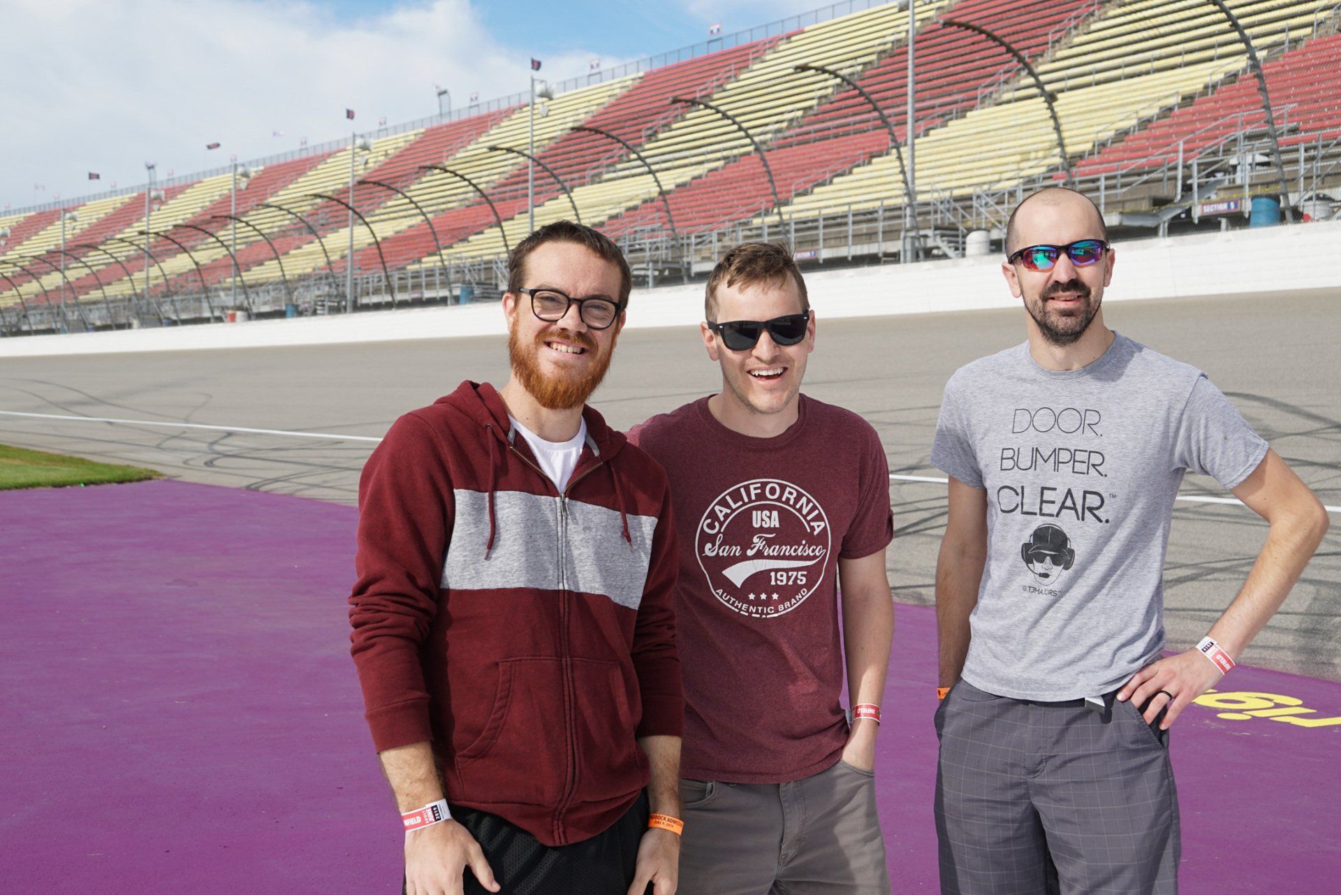 Three men are posing for a picture on a race track.