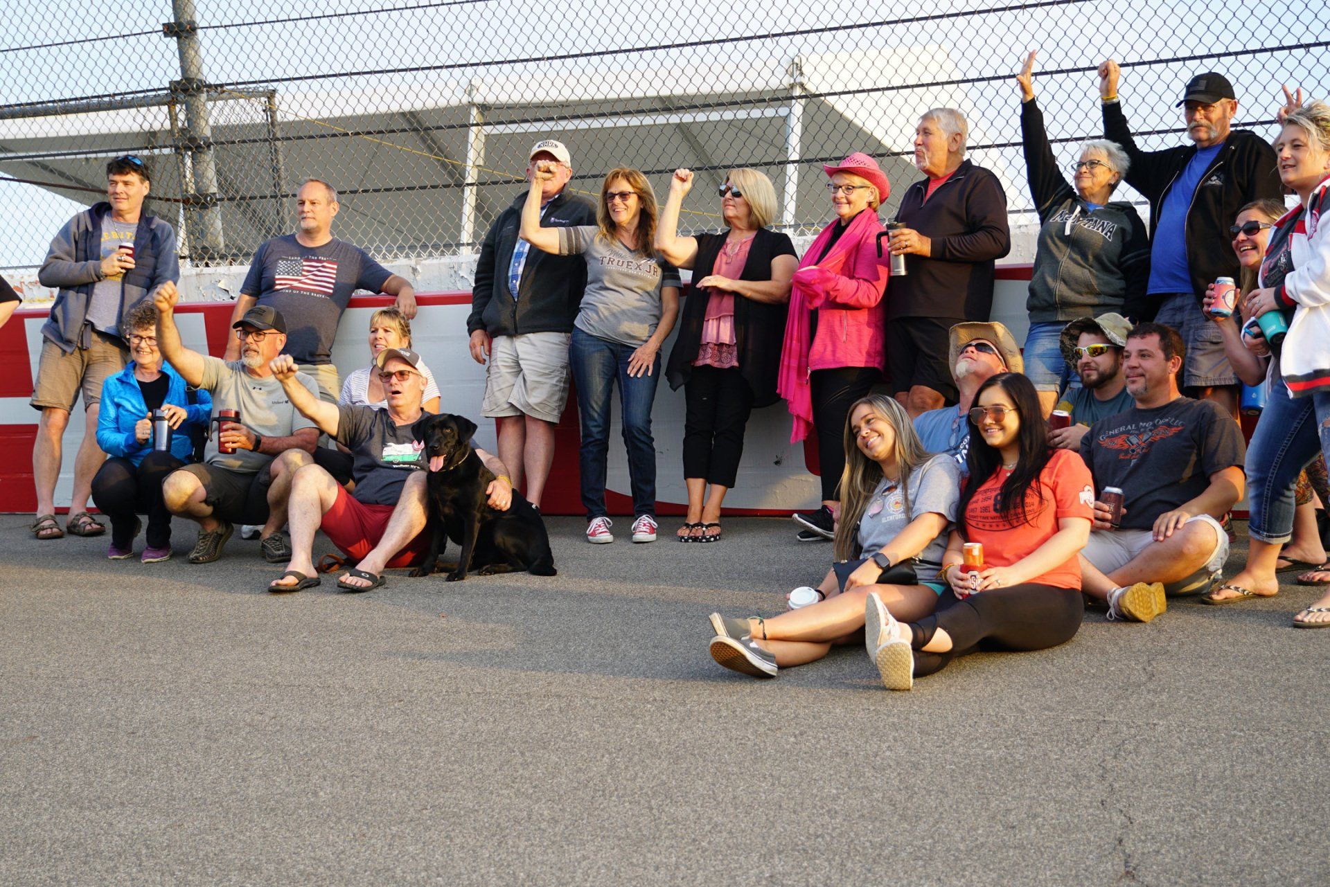 A group of people are posing for a picture in front of a fence.