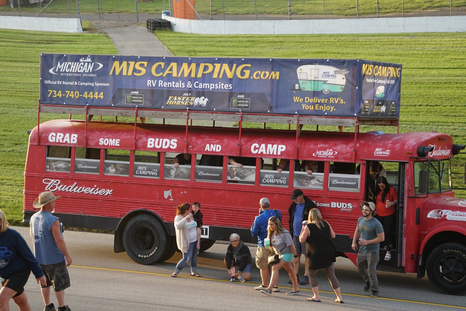 People are boarding a red bus that says mis camping.com