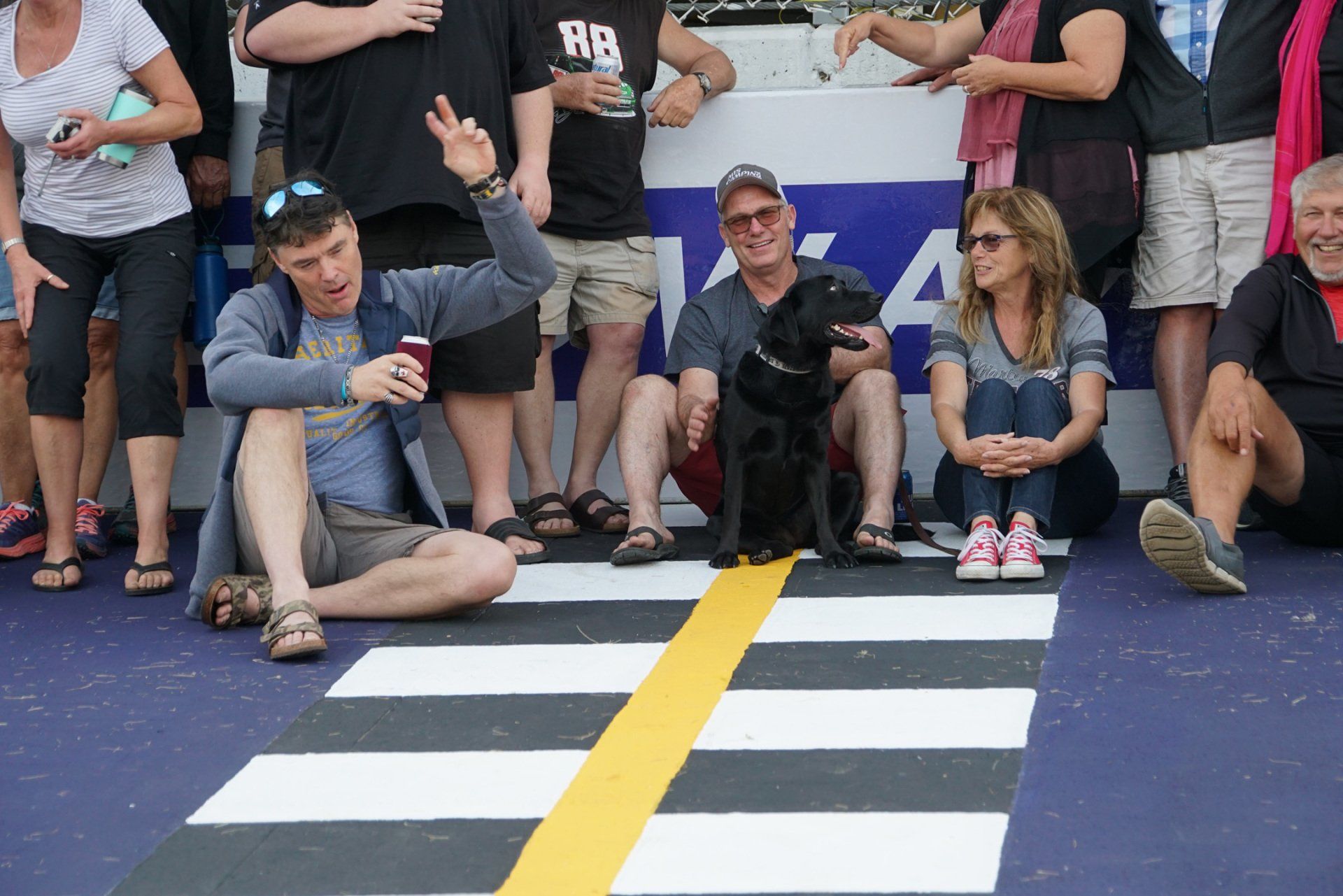 A group of people are sitting on the ground in front of a sign that says rb