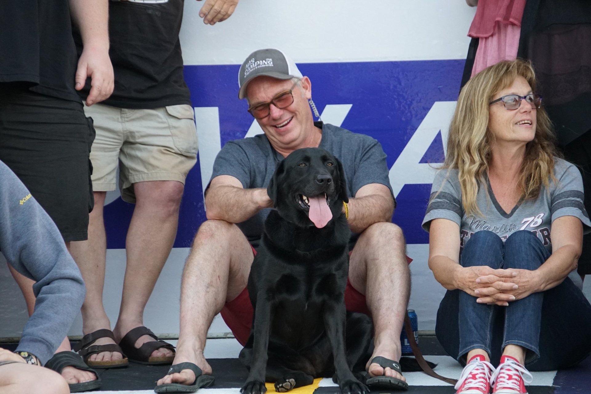 A man and a woman are sitting next to a black dog