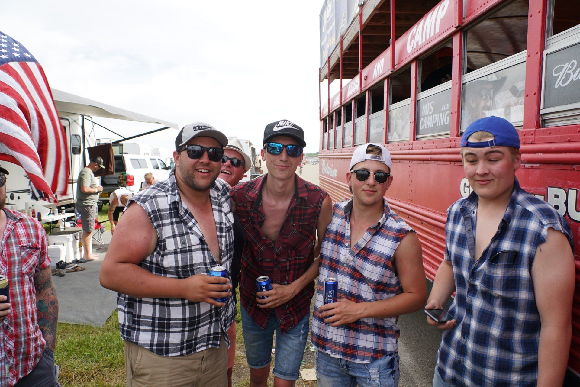 A group of men are posing for a picture in front of a red bus that says camp