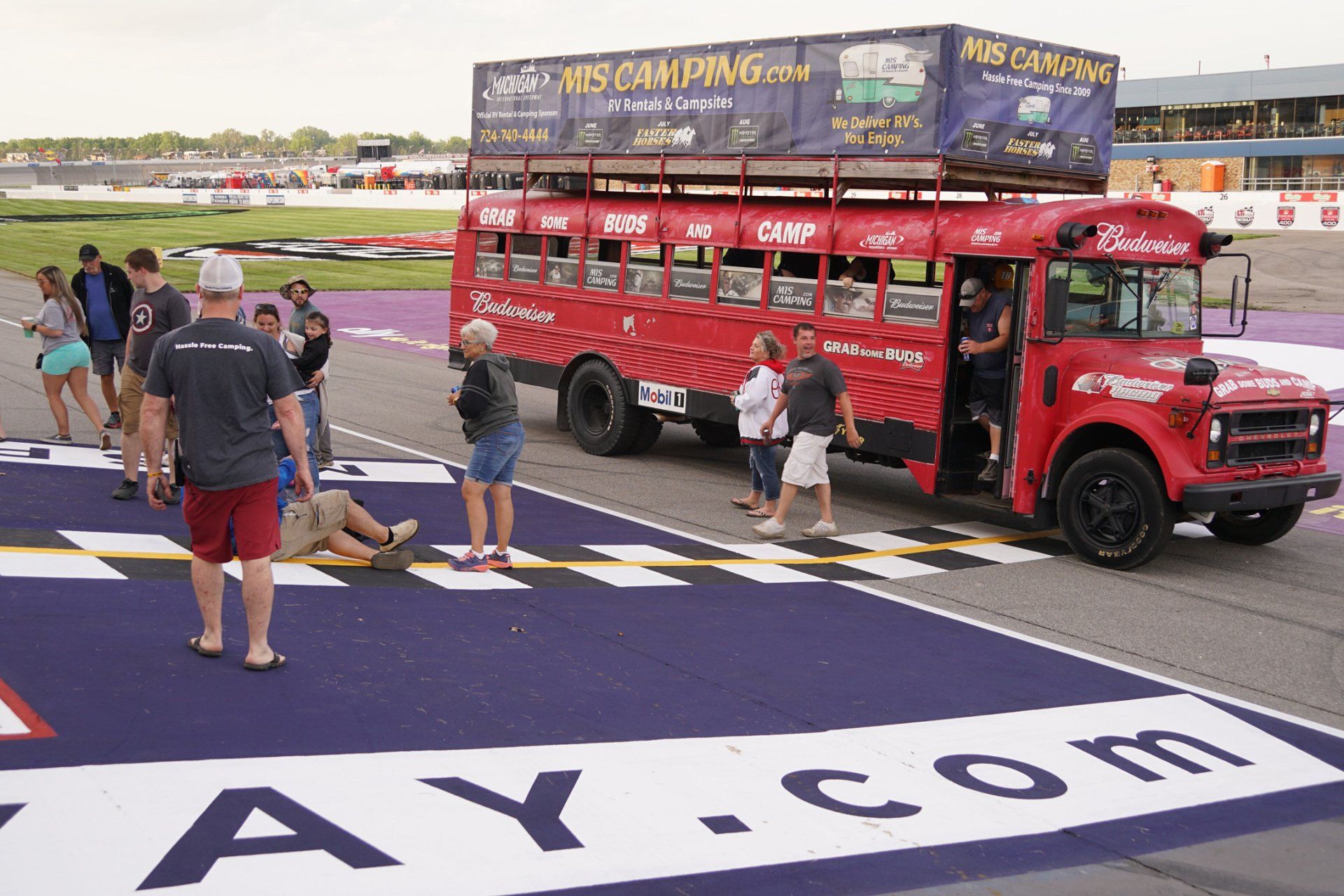 A red bus is parked on the side of a race track
