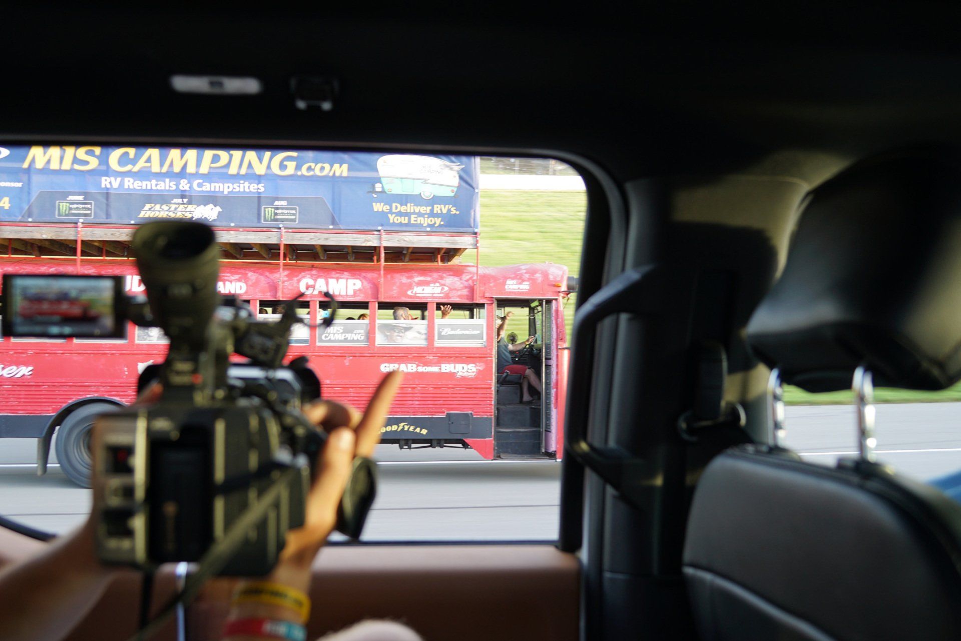 A person is taking a picture of a red bus with a sign that says mis camping.com