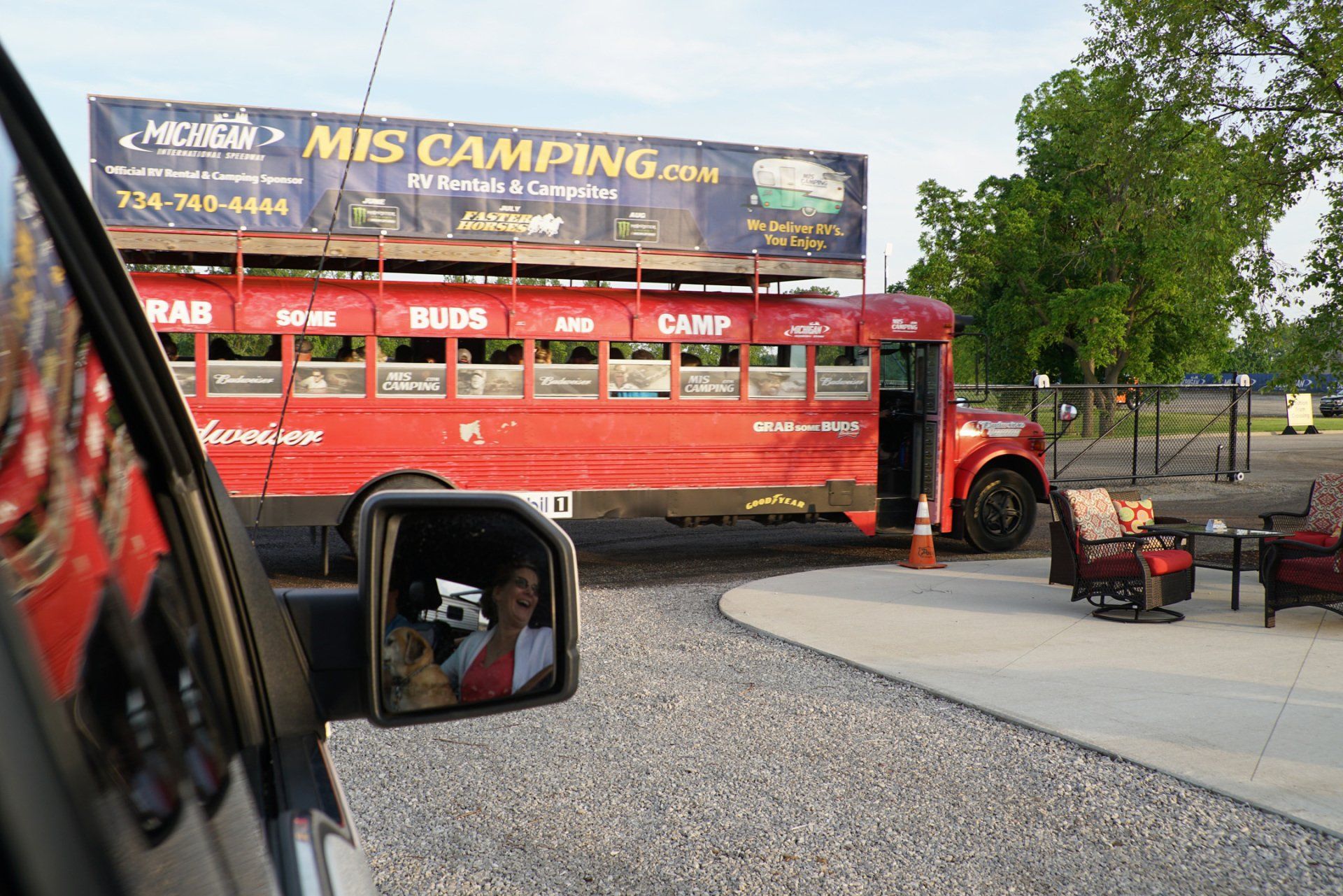 A red bus is parked in front of a sign that says mis camping