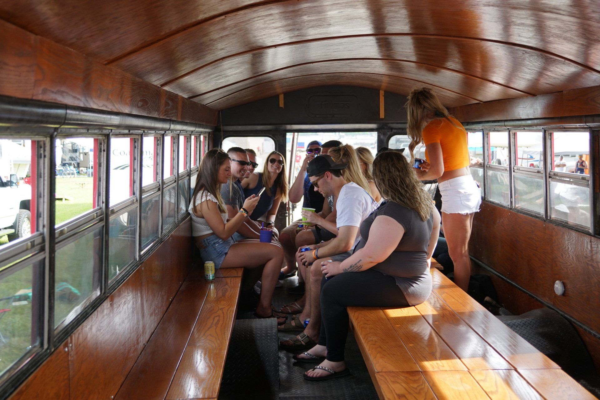 A group of people are sitting on wooden benches in a bus.
