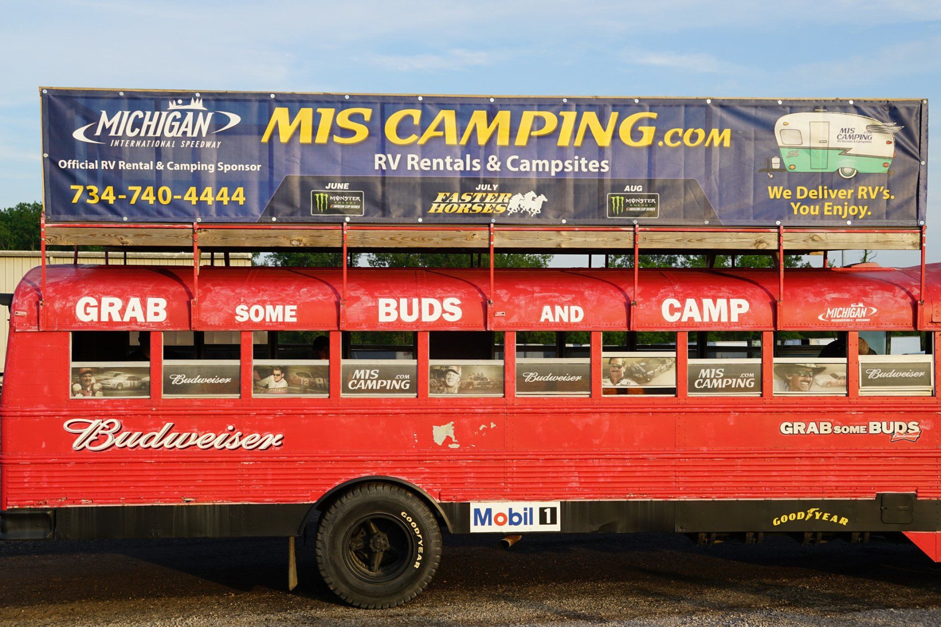 A red bus that says grab some buds and camp