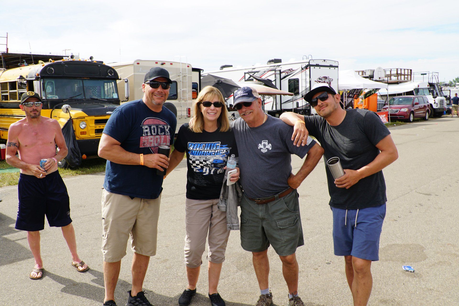 A group of people are posing for a picture in front of buses