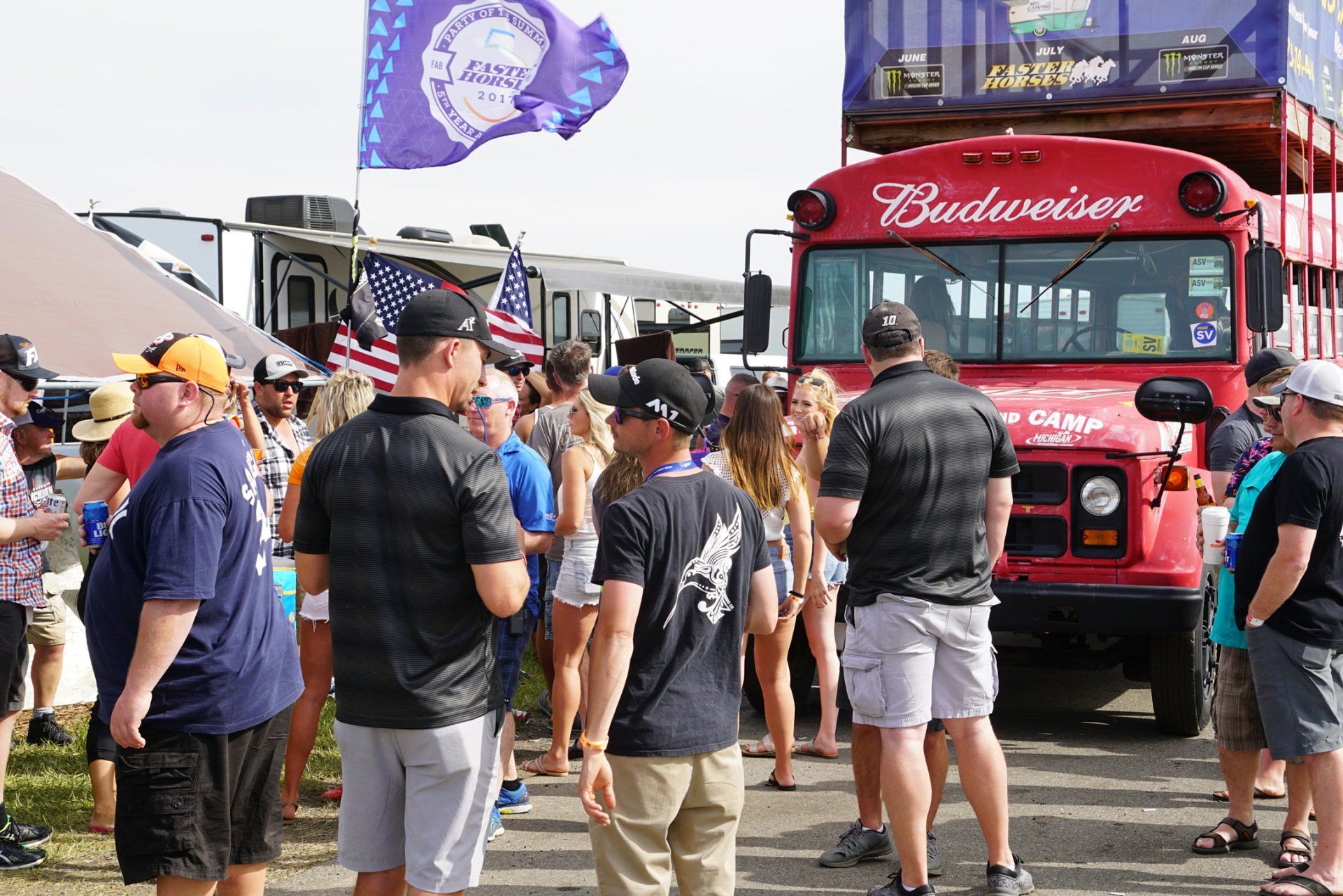 A group of people standing in front of a budweiser bus