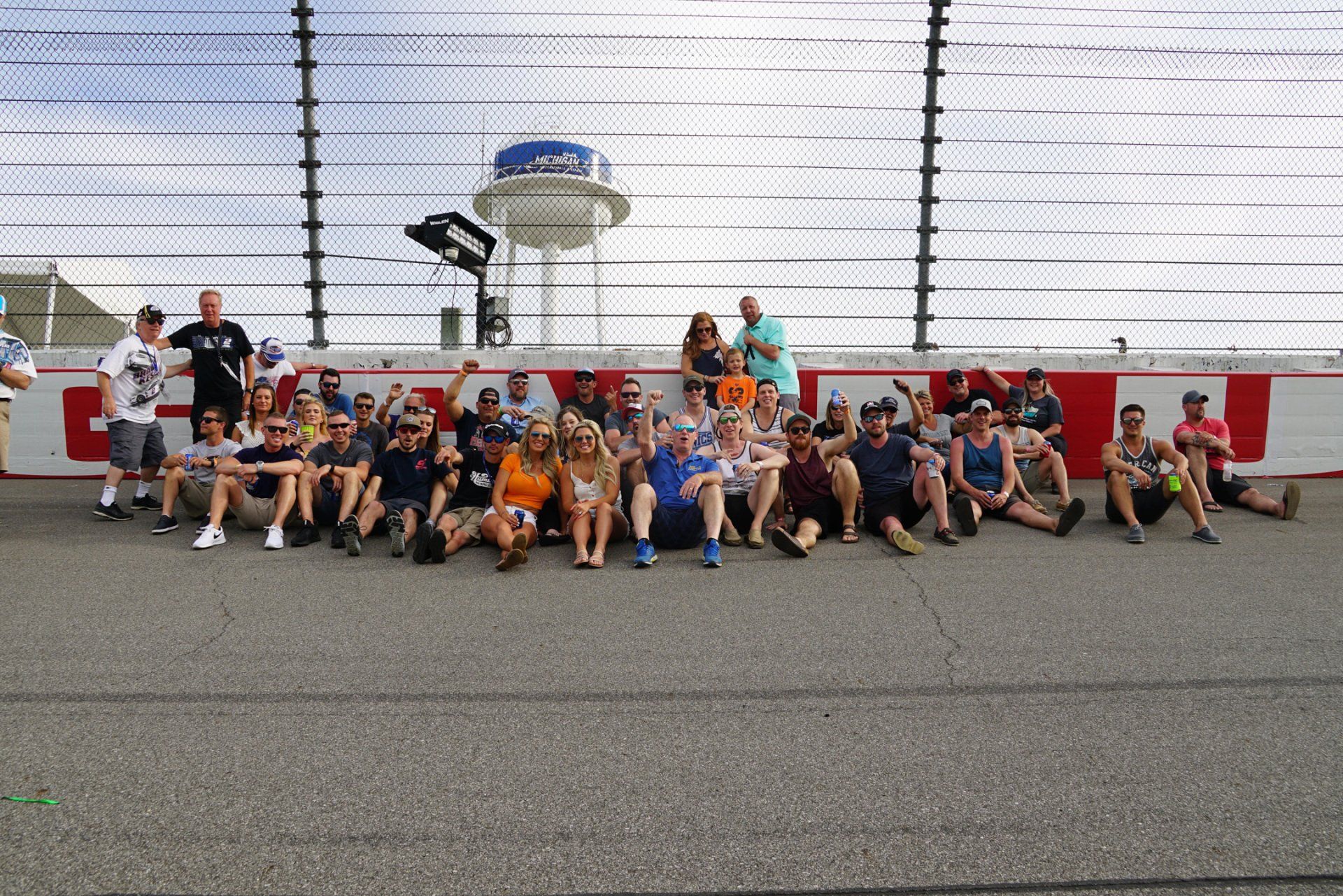 A group of people are posing for a picture on a race track.
