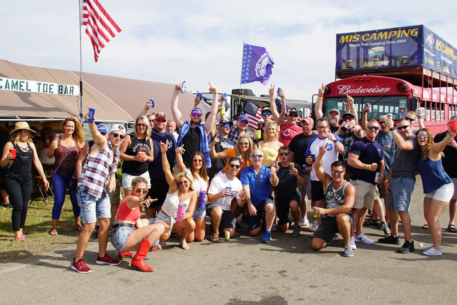 A group of people posing for a picture in front of a budweiser bus