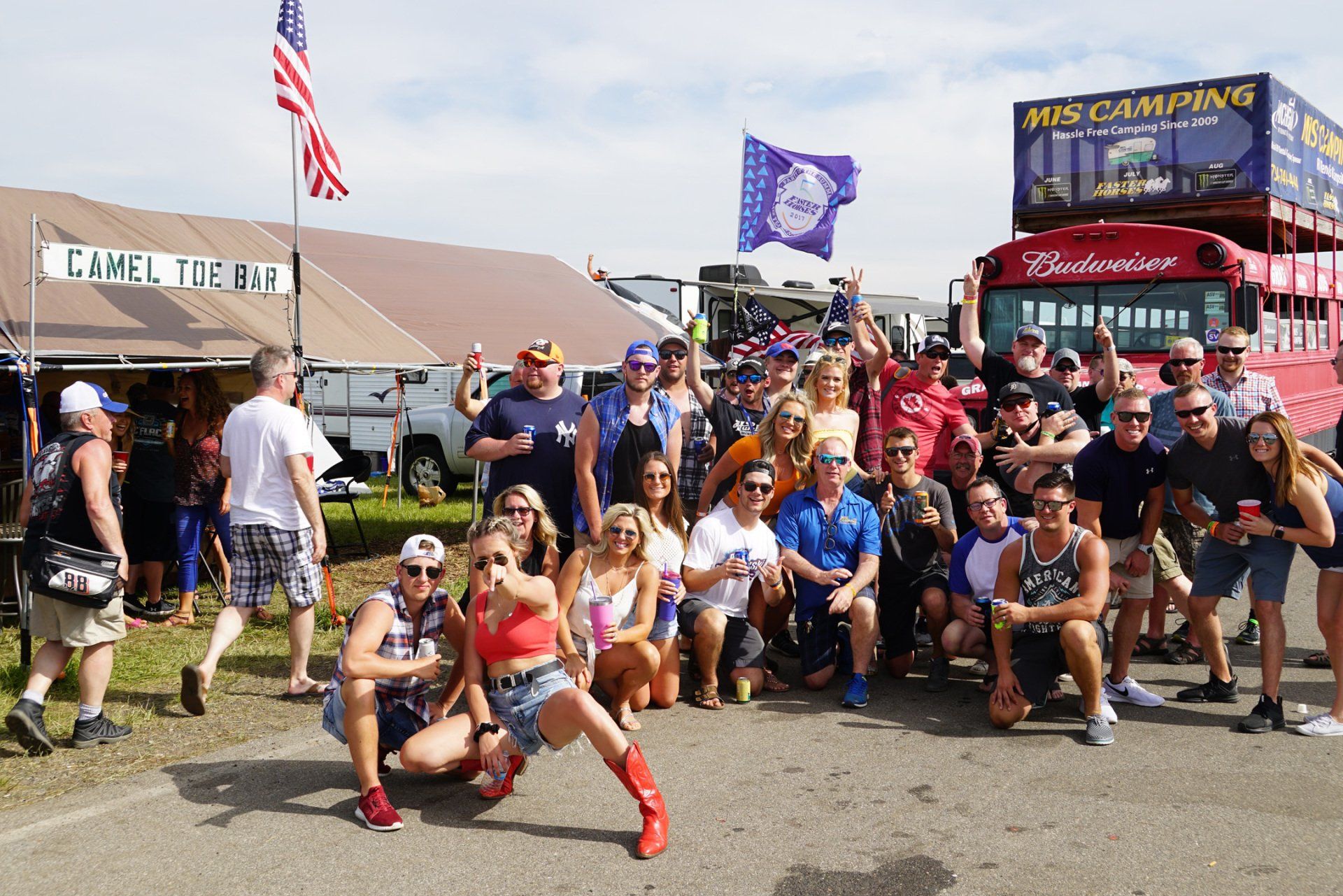 A group of people posing for a picture in front of a budweiser bus
