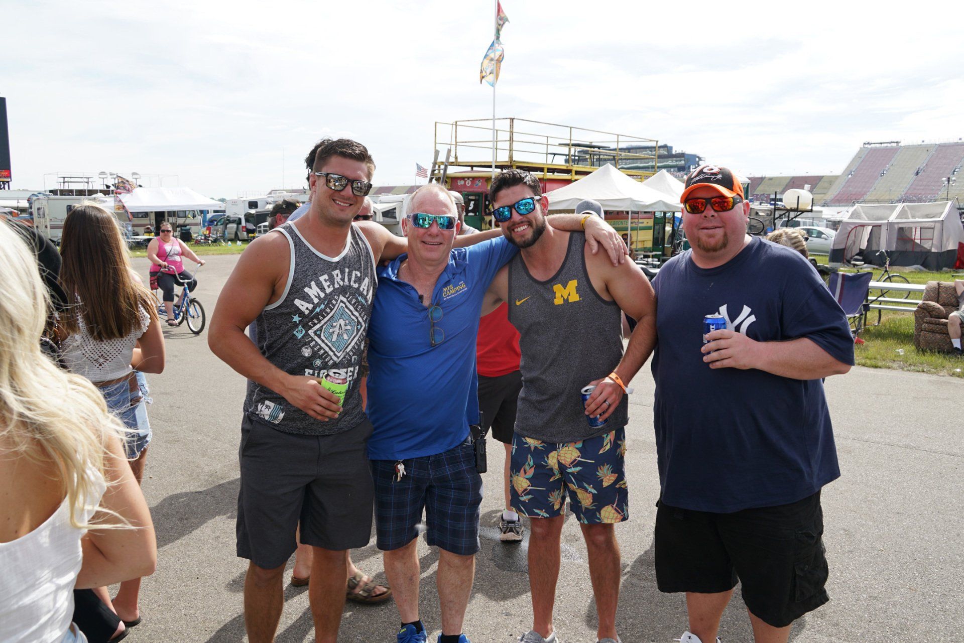 A group of men posing for a picture with one wearing a tank top with the letter m on it