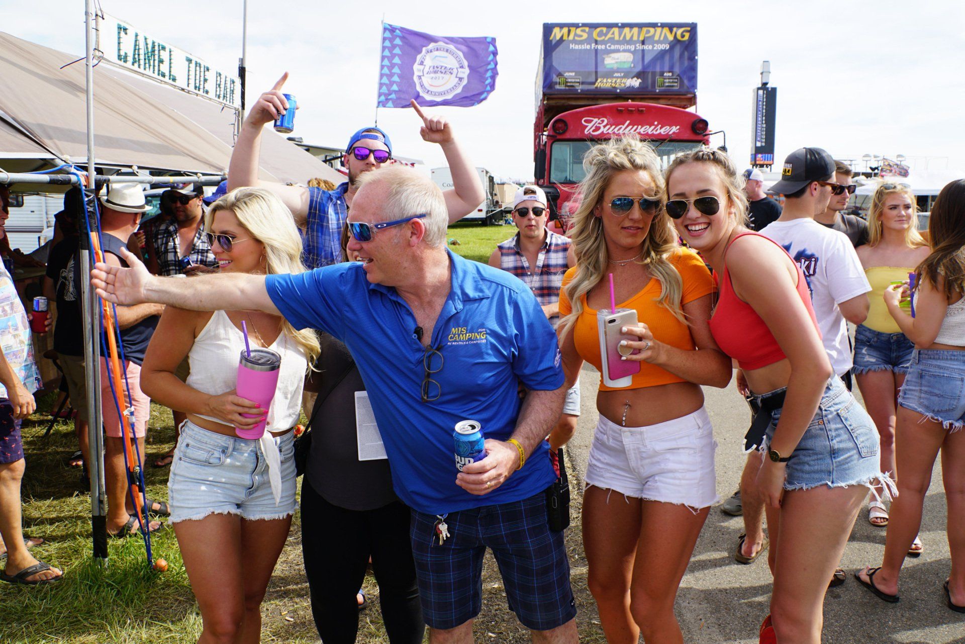 A group of people are posing for a picture in front of a sign that says camel
