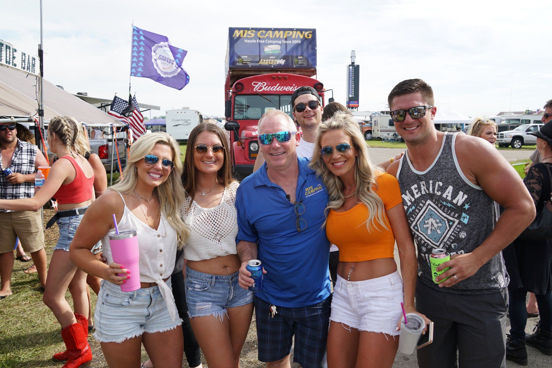 A group of people posing for a picture in front of a budweiser bus