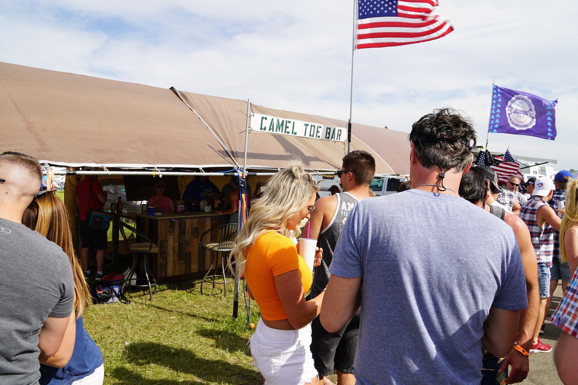 A group of people are standing in front of a camel tech tent.
