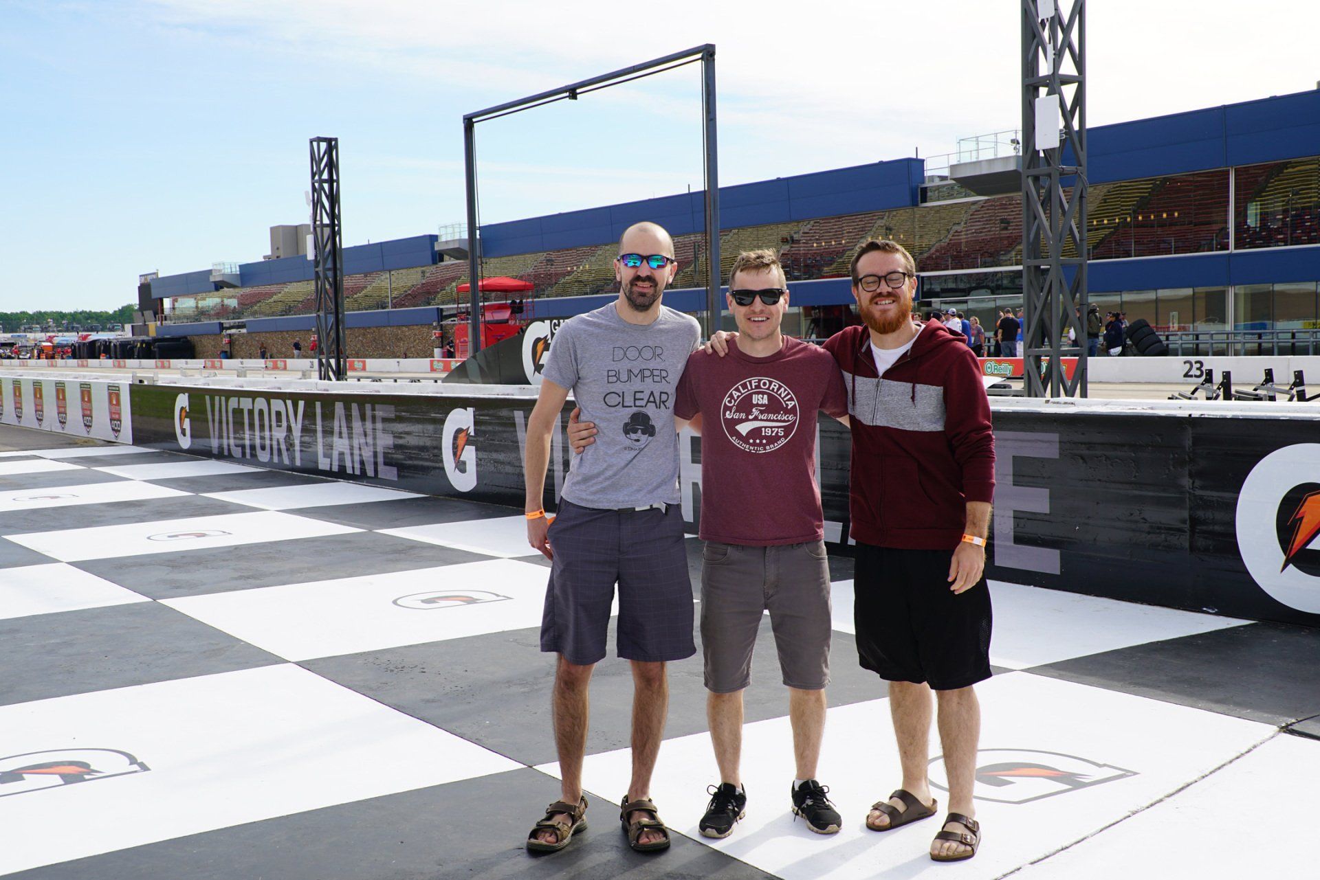 Three men are posing for a picture in front of a gatorade sign.