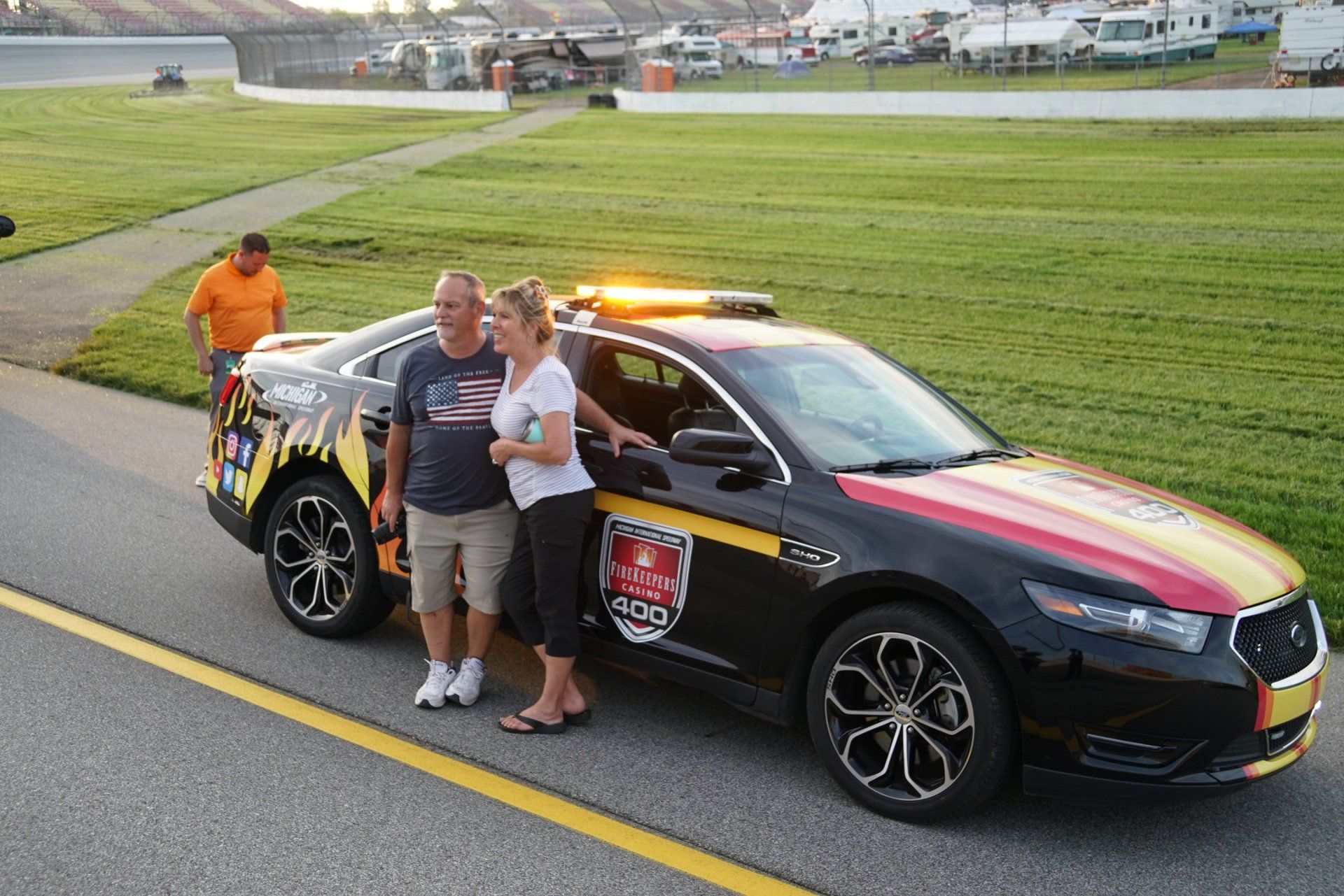 A man and a woman are standing next to a police car