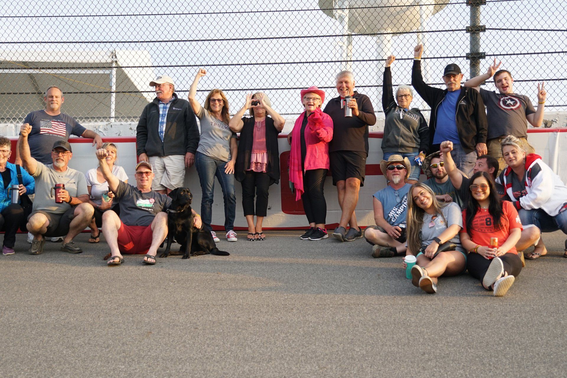 A group of people are posing for a picture in front of a fence.